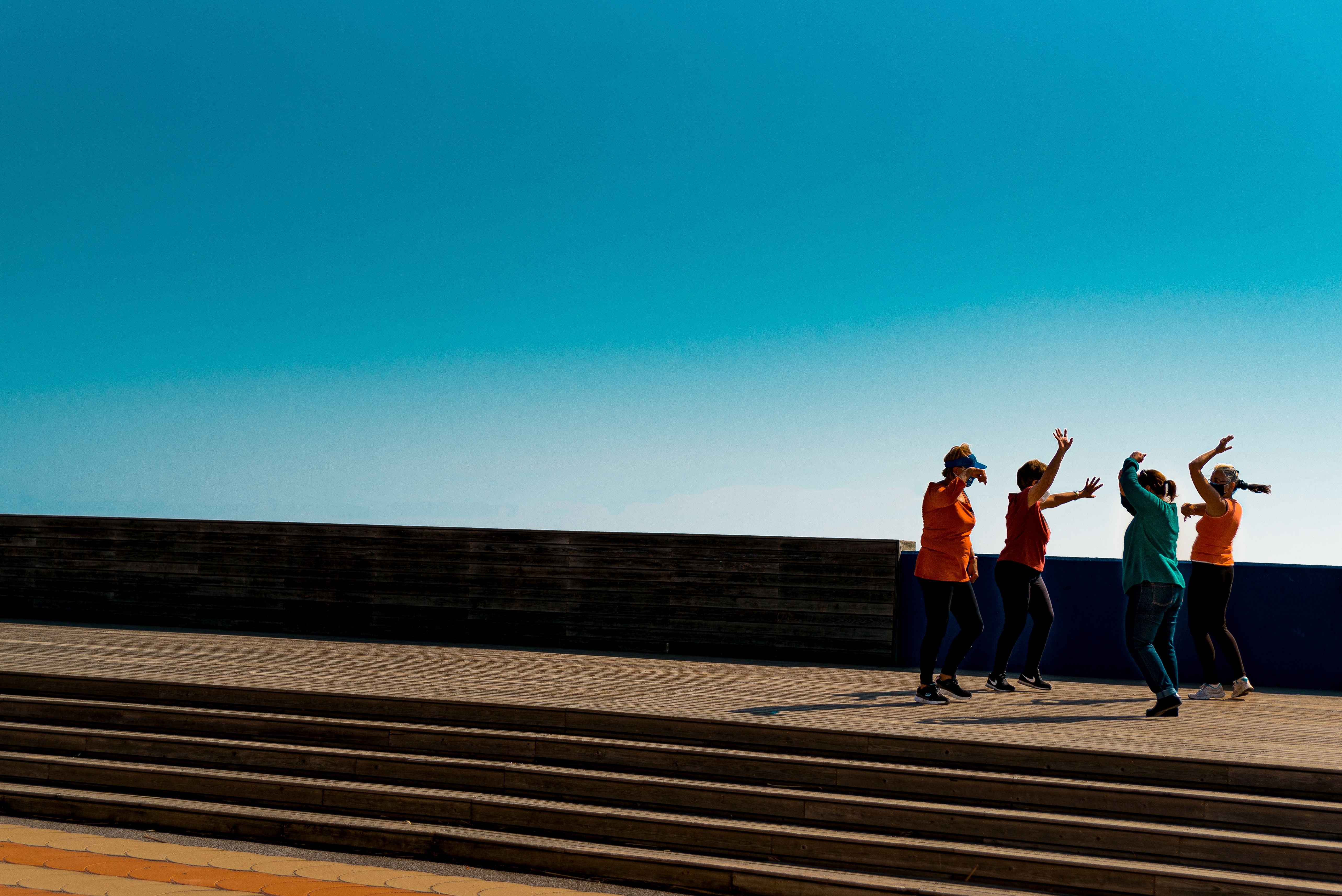 A group of women dance against the blue Barcelona sky on a sunny Sunday morning, after the end of lockdown.