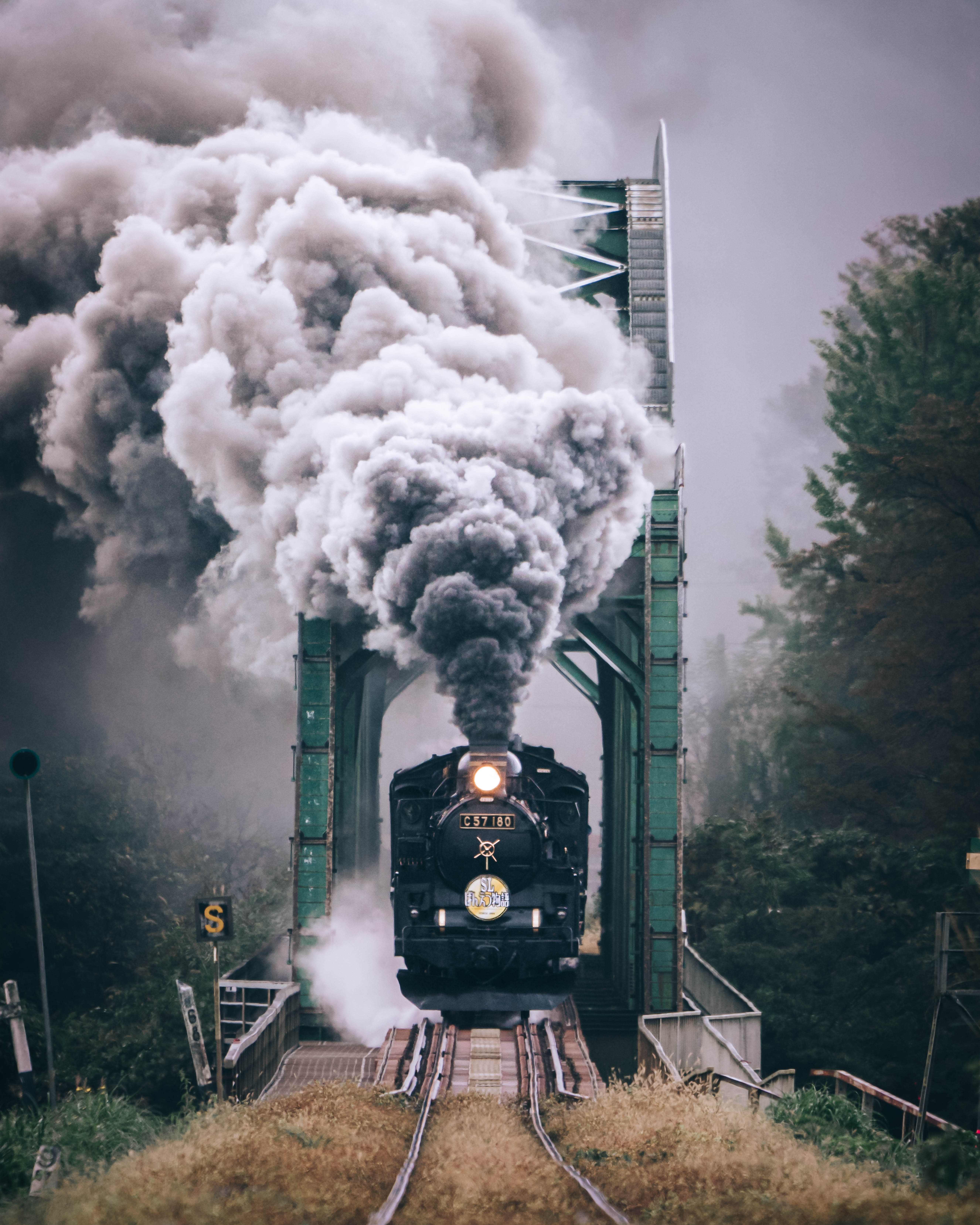 A steam train crosses a railway bridge.
