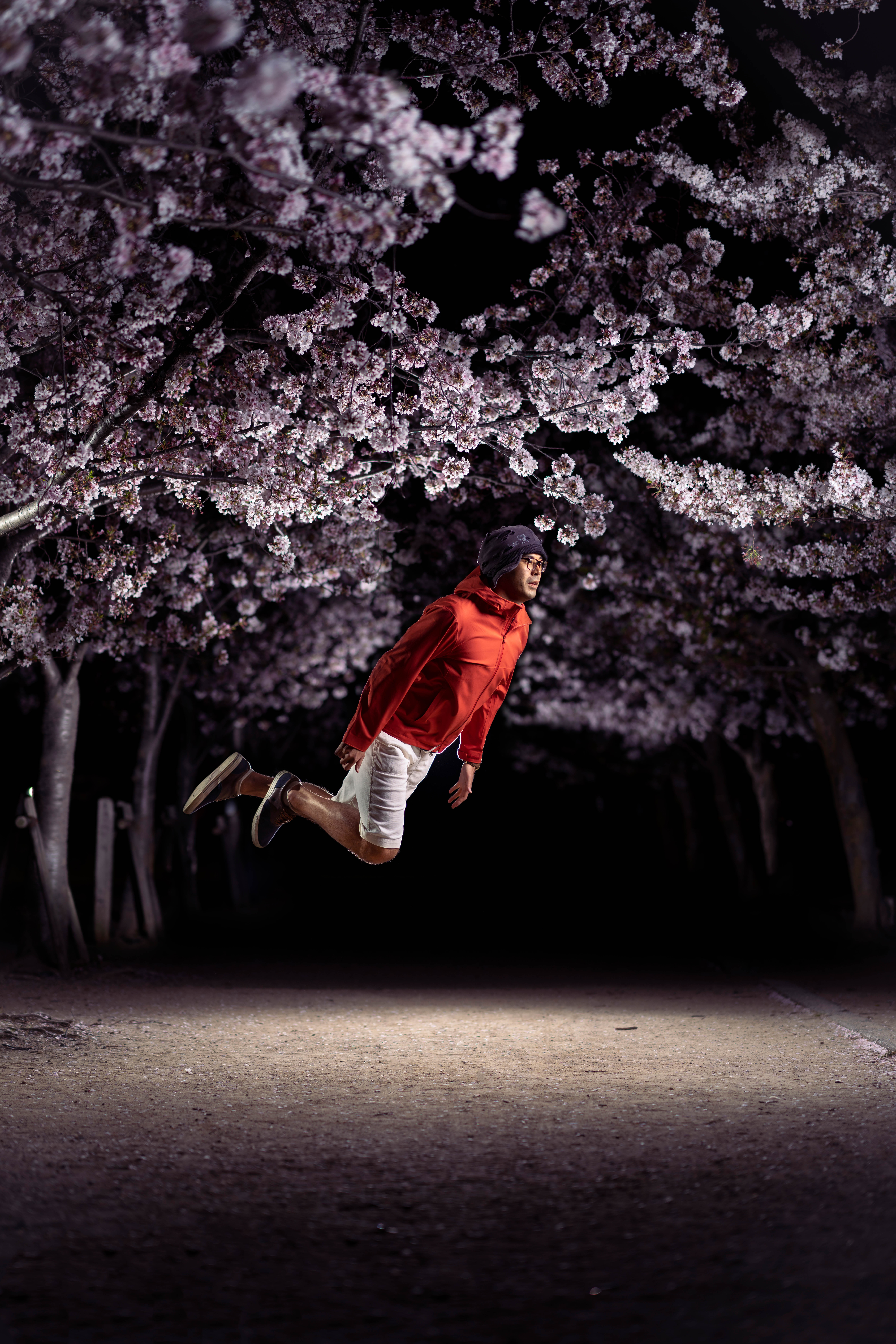A man jumps in front of cherry blossoms.