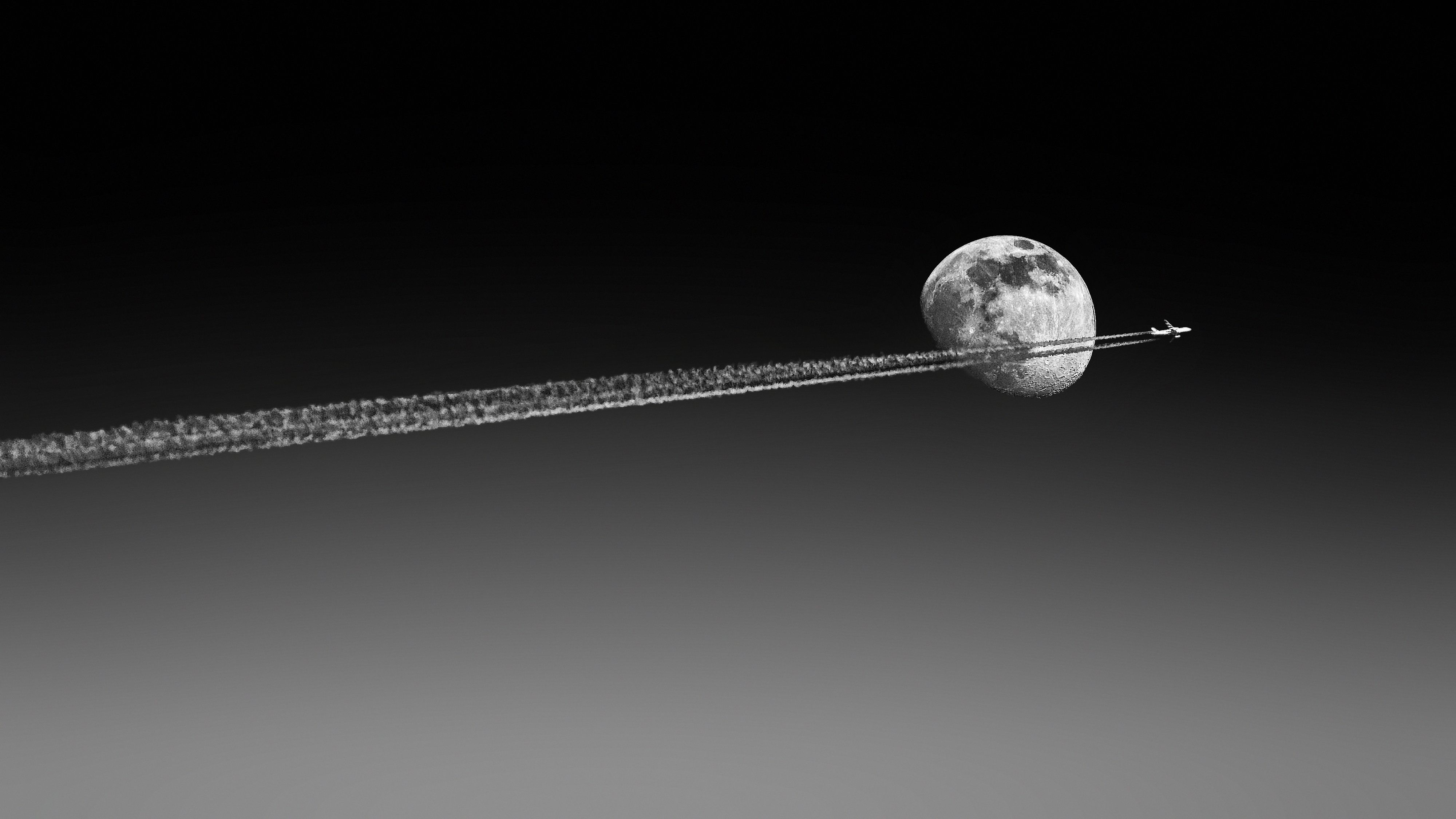 A plane flies past the moon.