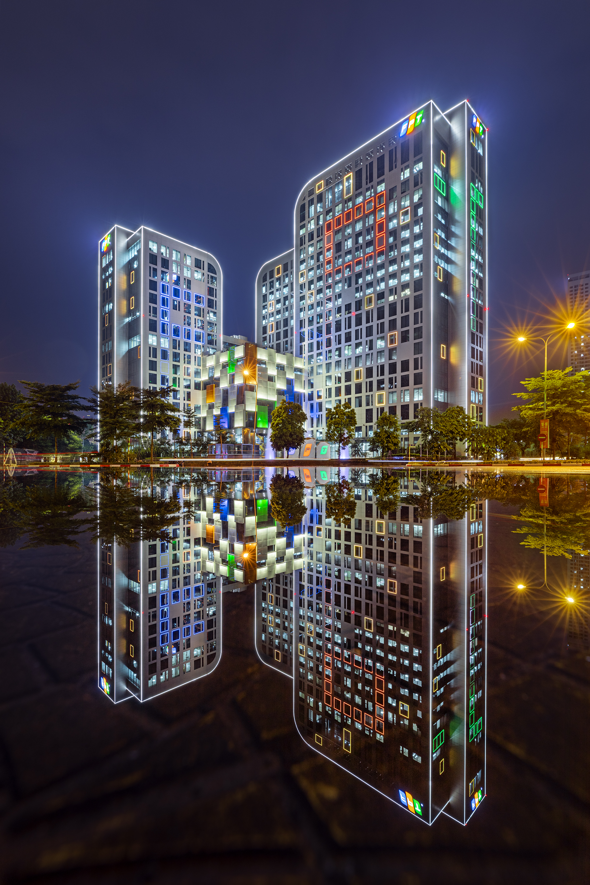 Hanoi FPT Corporation's building reflected on the street, on a rainy night.