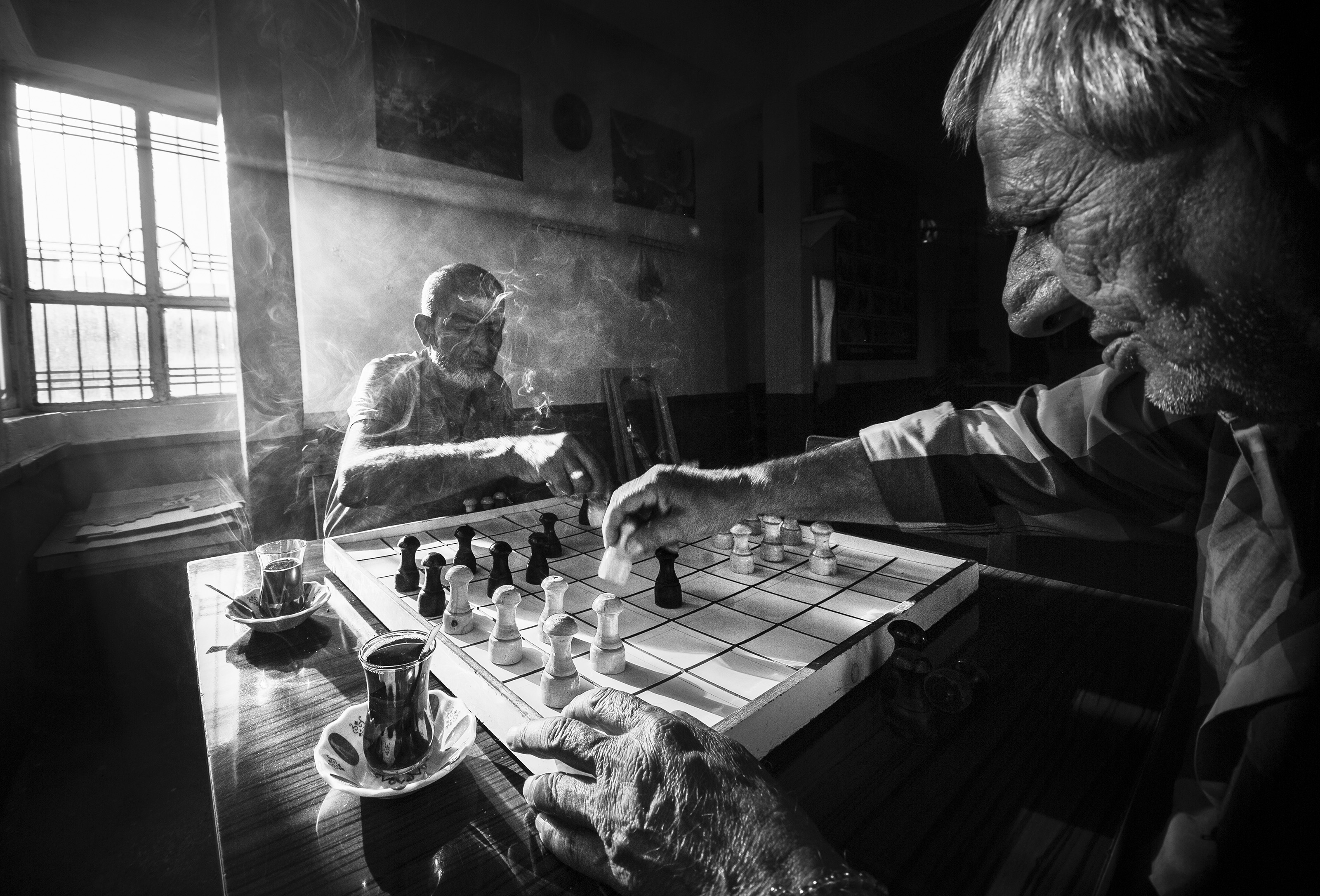 Two old friends play chess in a cafe.
