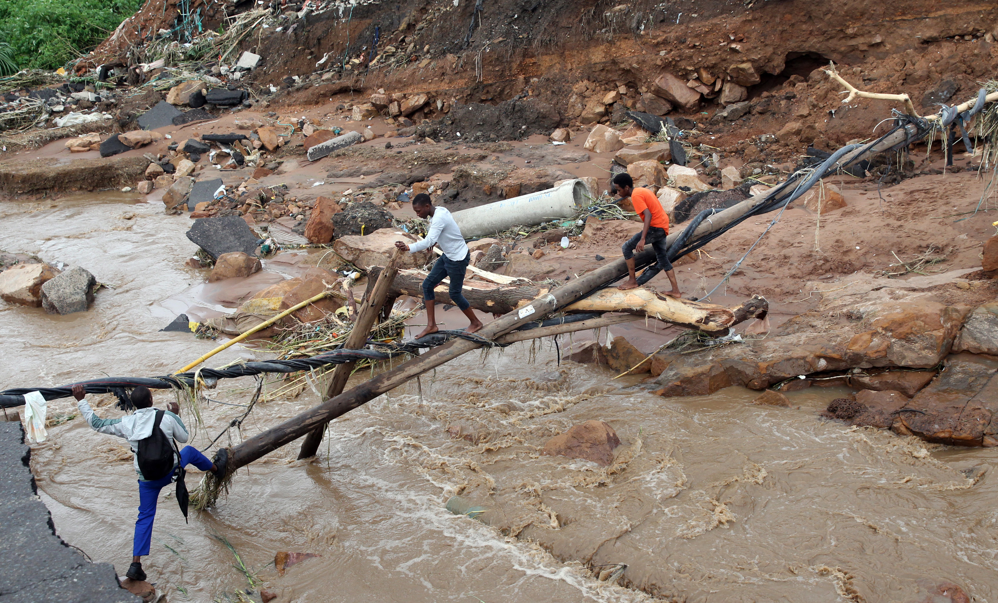KZN floods - People trying to cross a river in Ntuzuma where a bridge was washed away.