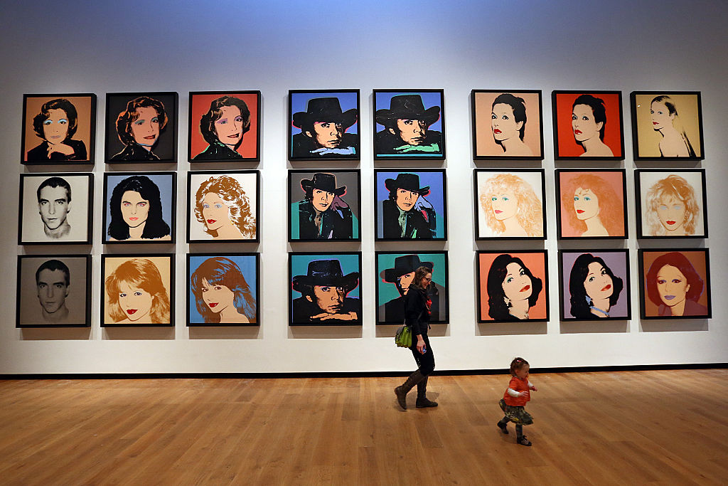 A member of staff and her child walk next to a series of artworks by Andy Warhol at the Ashmolean Museum on February 2, 2016 in Oxford, England.