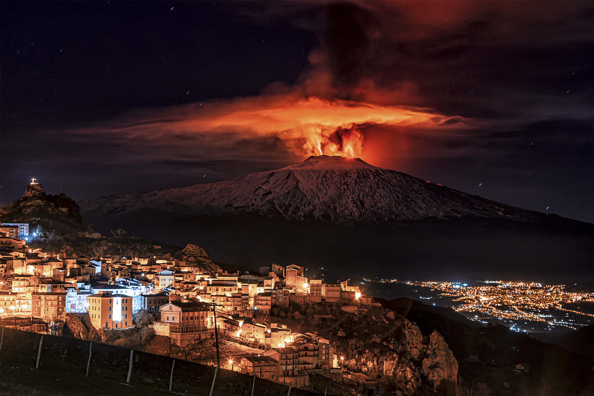 This night eruption of the Etna volcano was taken from San Teodoro at 2 am. Three eruptive vents are seen, which simultaneously eject columns of lava up to 1000 metres high. The town in the foreground is Cesarò, and the lights at the bottom are from the municipality of Bronte.