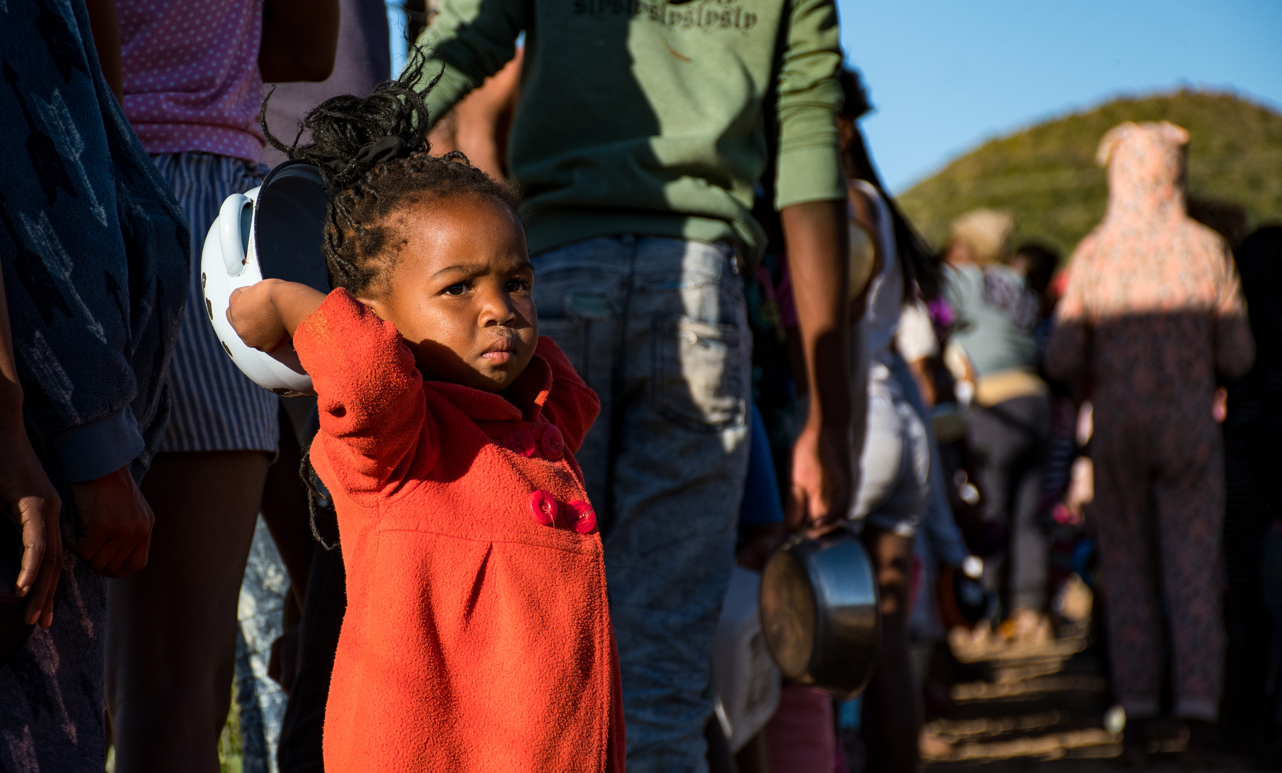 A young girl with her tin bowl in the soup kitchen line at Vrygronde community's feeding scheme