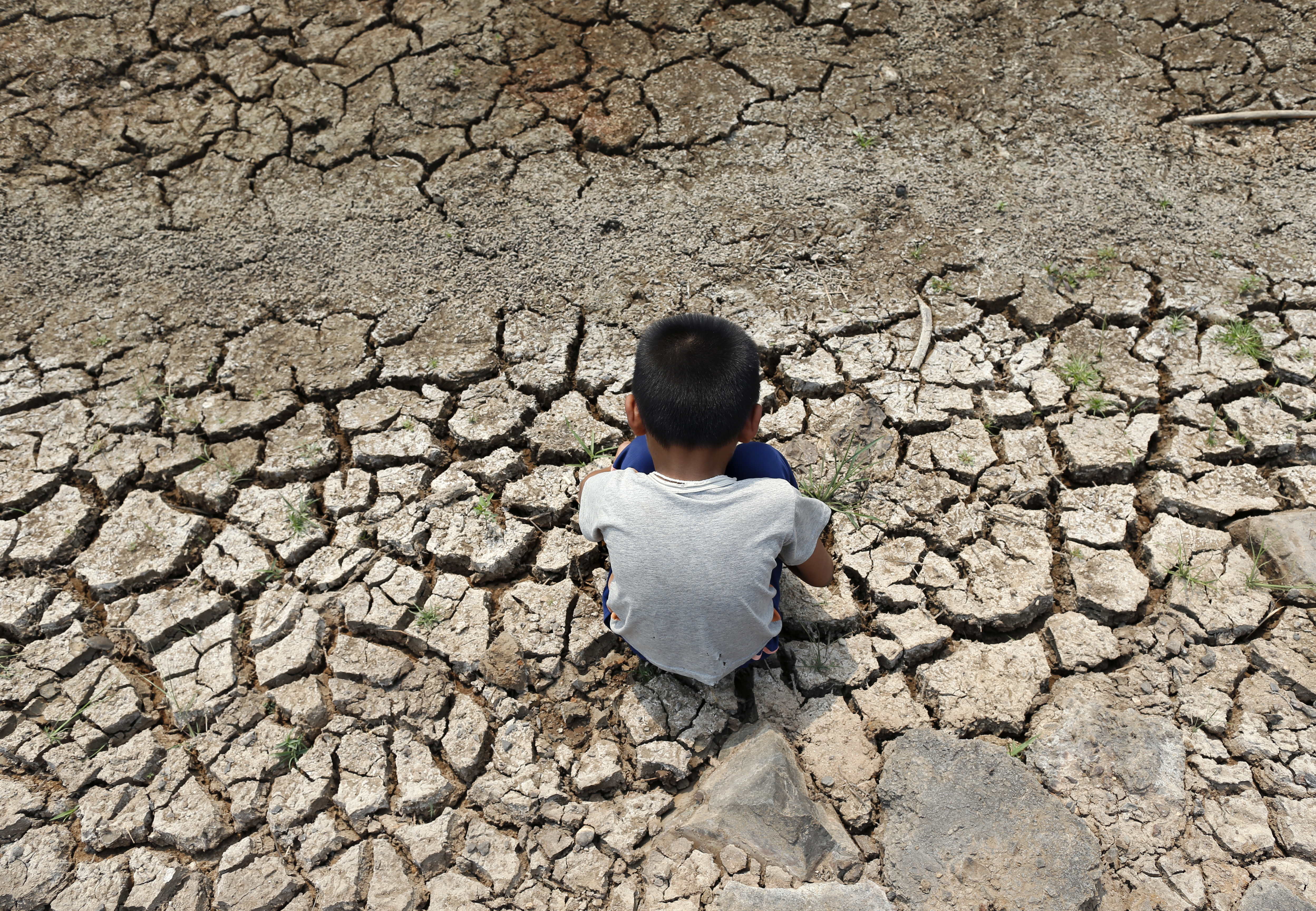 a Thai villager boy sits on drought parched land at a dried up irrigation canal in Chachoengsao province, Thailand, 05 March 2016.