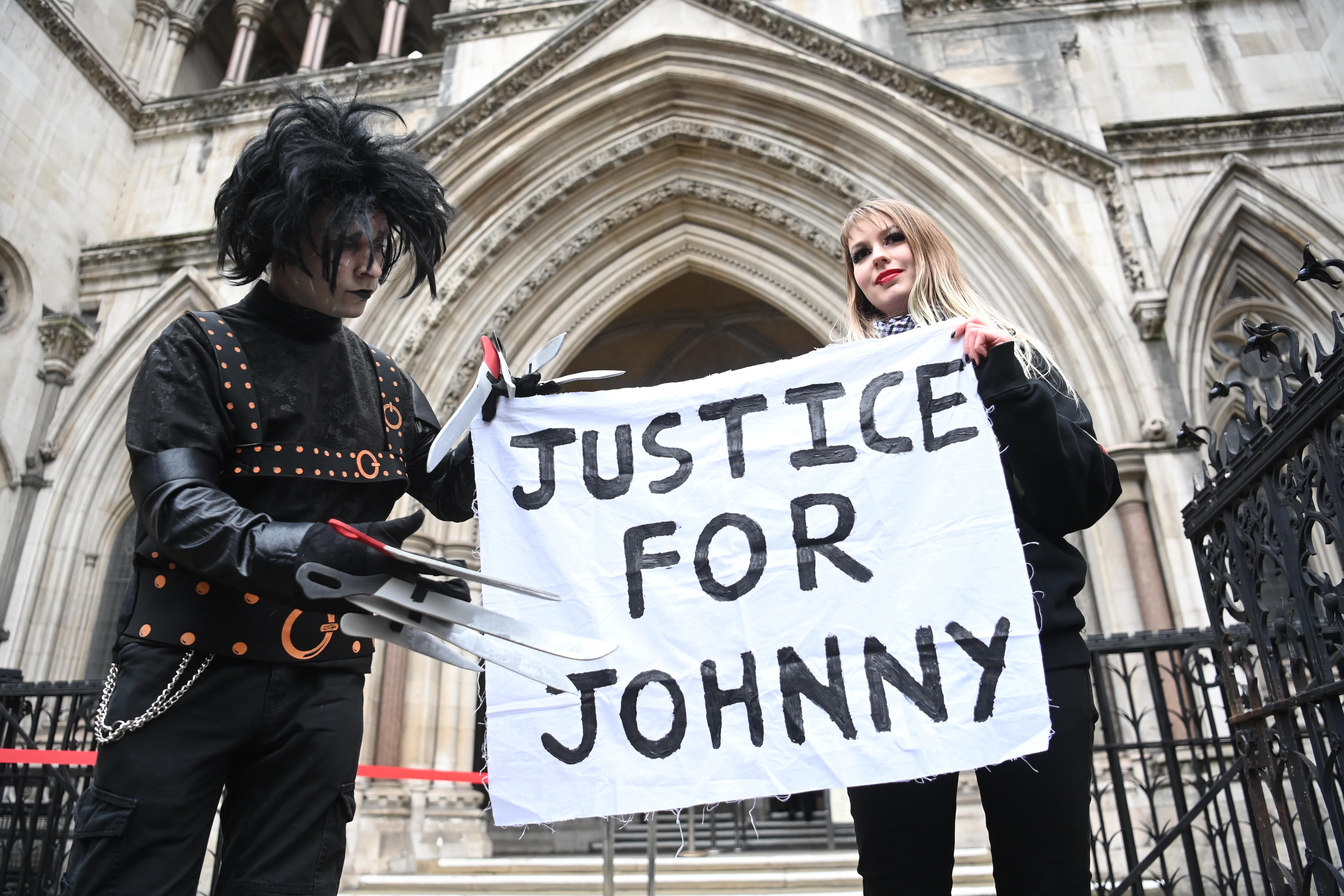 Fans in costume display a banner in support of US actor Johnny Depp outside the Royal Courts of Justice in London, Britain, 18 March 2021. 