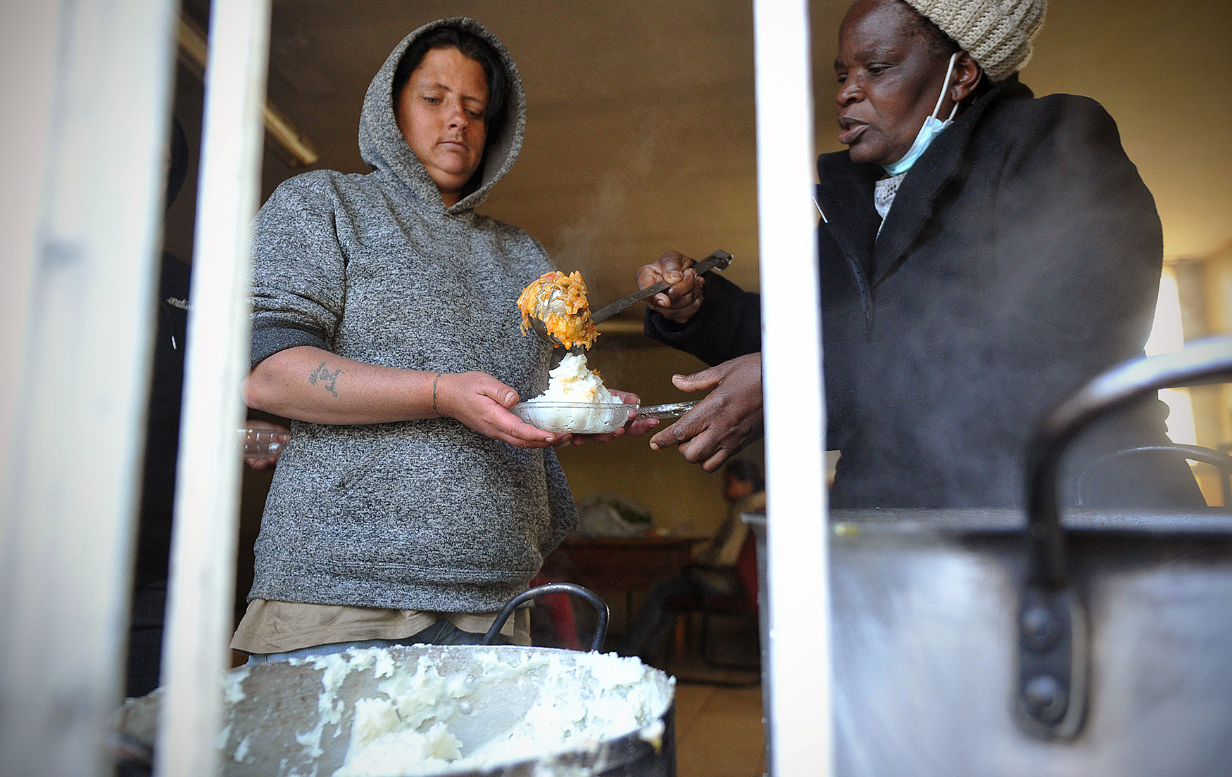 Refileo Molefe serves food to a member of her youth team at Bertrams Inner City Farm