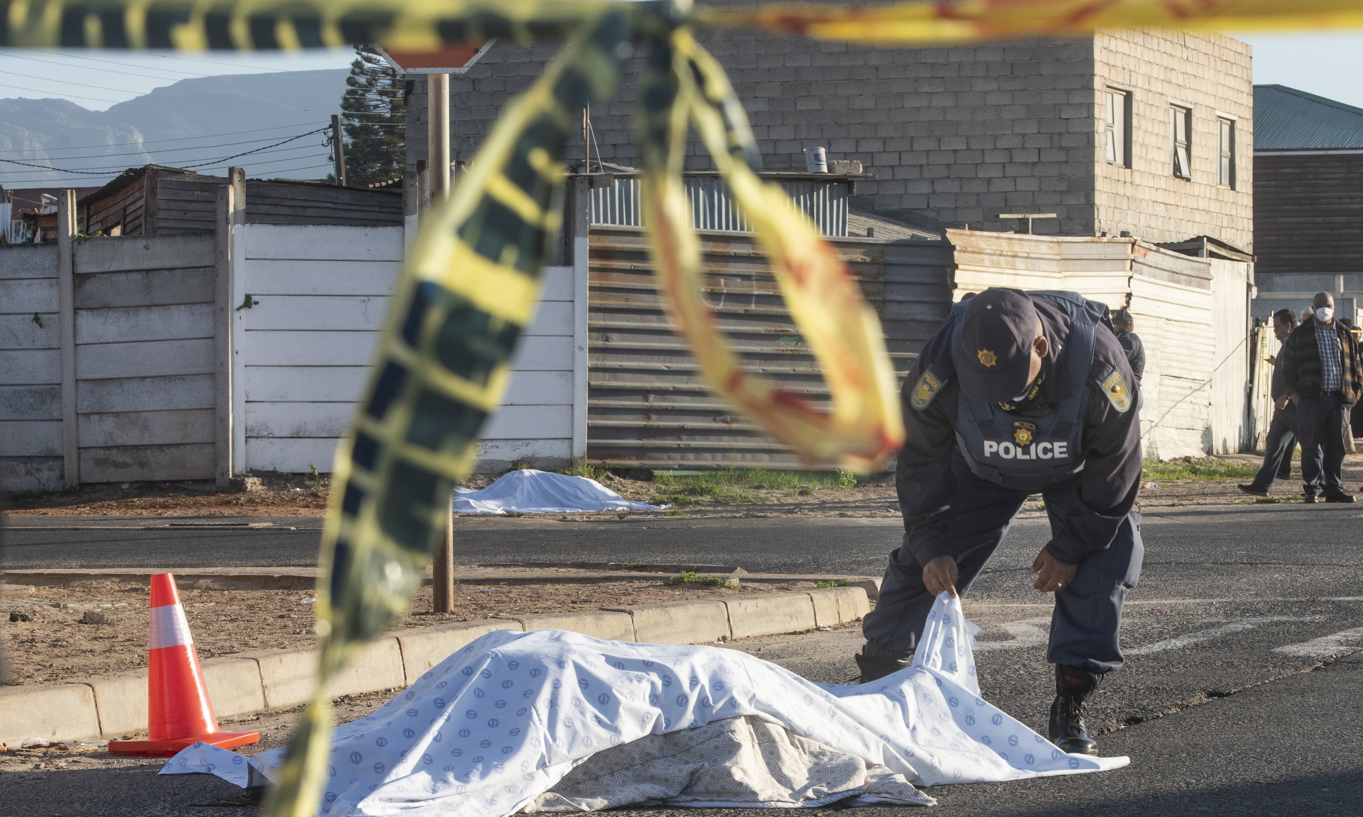 A police officer inspects the covered body of a shooting victim