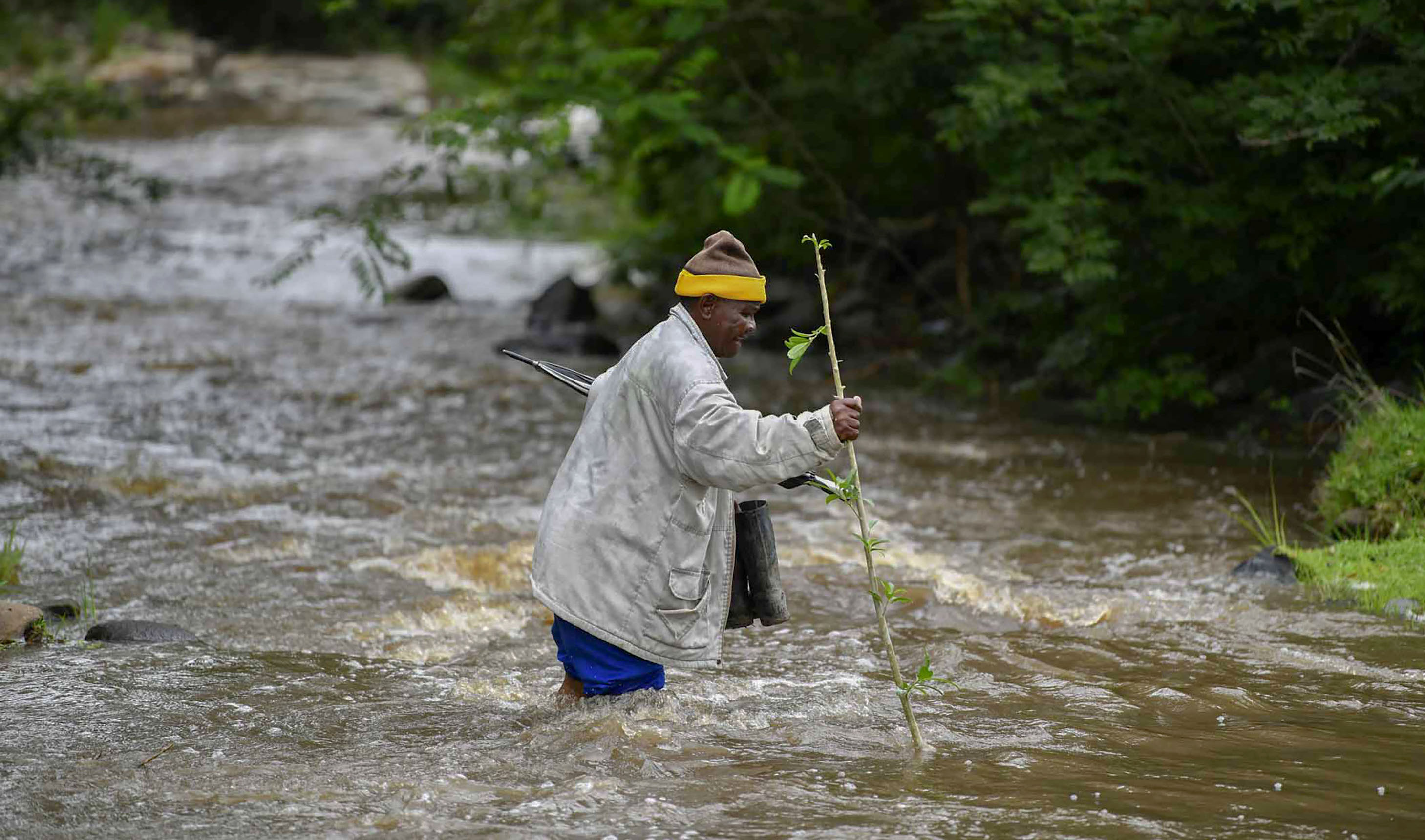 An image of a resident crossing a river in knee-deep water to reach a clinic