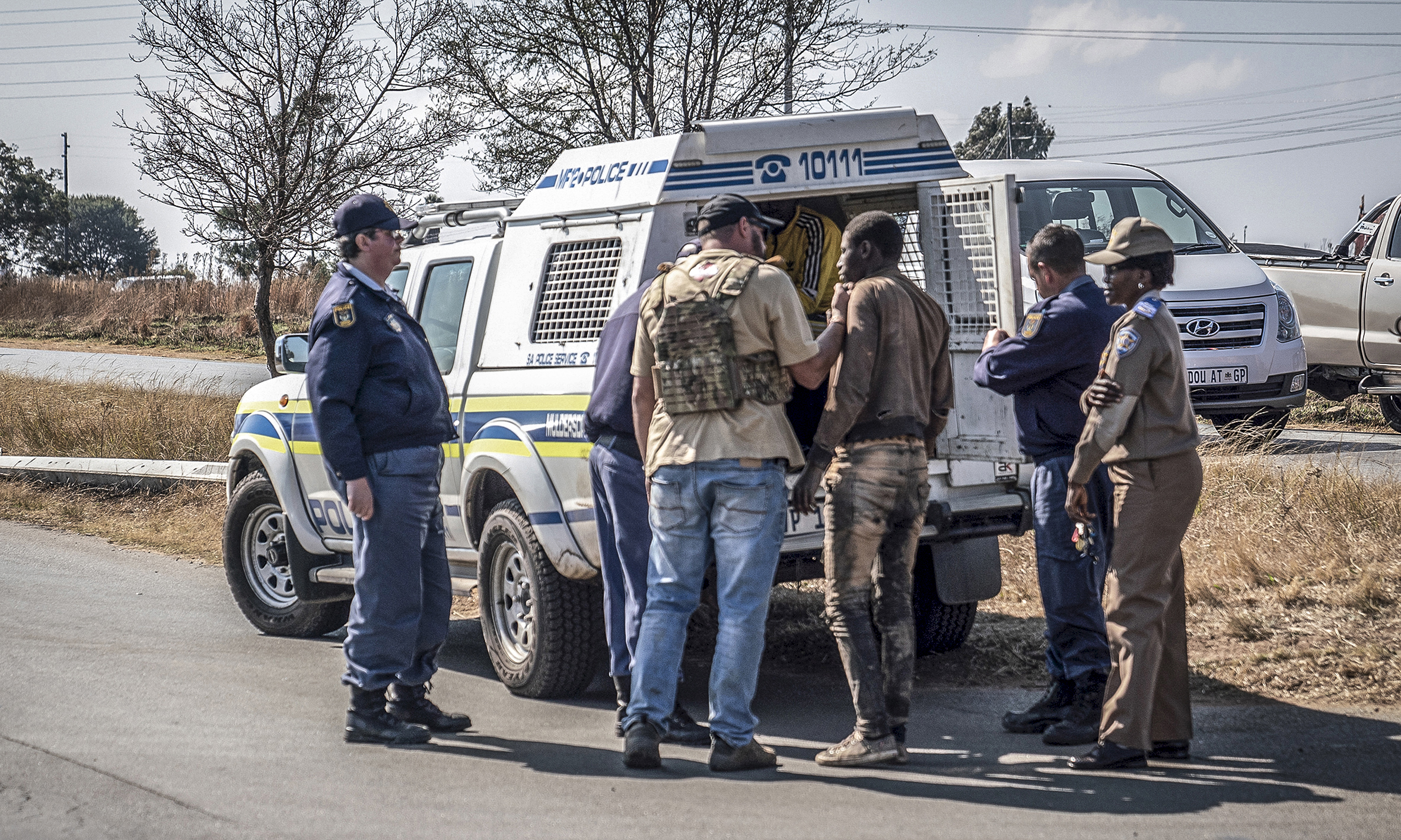 A man believed to be a zama zama is loaded into a police van