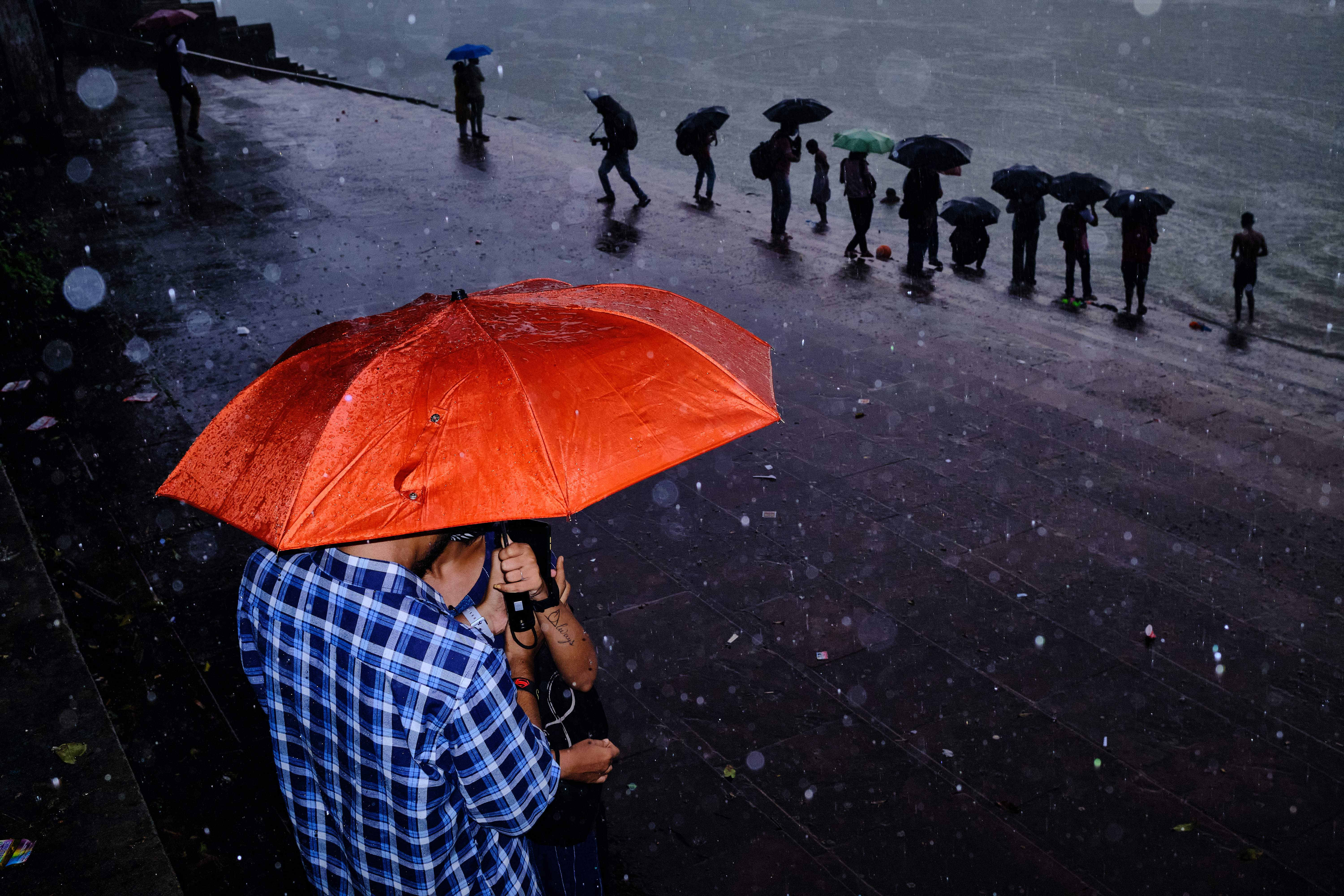 Monsoon in my city. "I took this picture in Kolkata, India. Whenever it rains, I love to use flash. I saw this couple having a moment away from the crowd in the heavy rain. I loved the orange umbrella, the colour stands out and in the background, people with umbrella creates an echo in the photograph. The internal flash was enough to create this dreamy effect in rain." © Subhran Karmakar, India, entry, Open Competition, Street Photography, 2023 Sony World Photography Awards