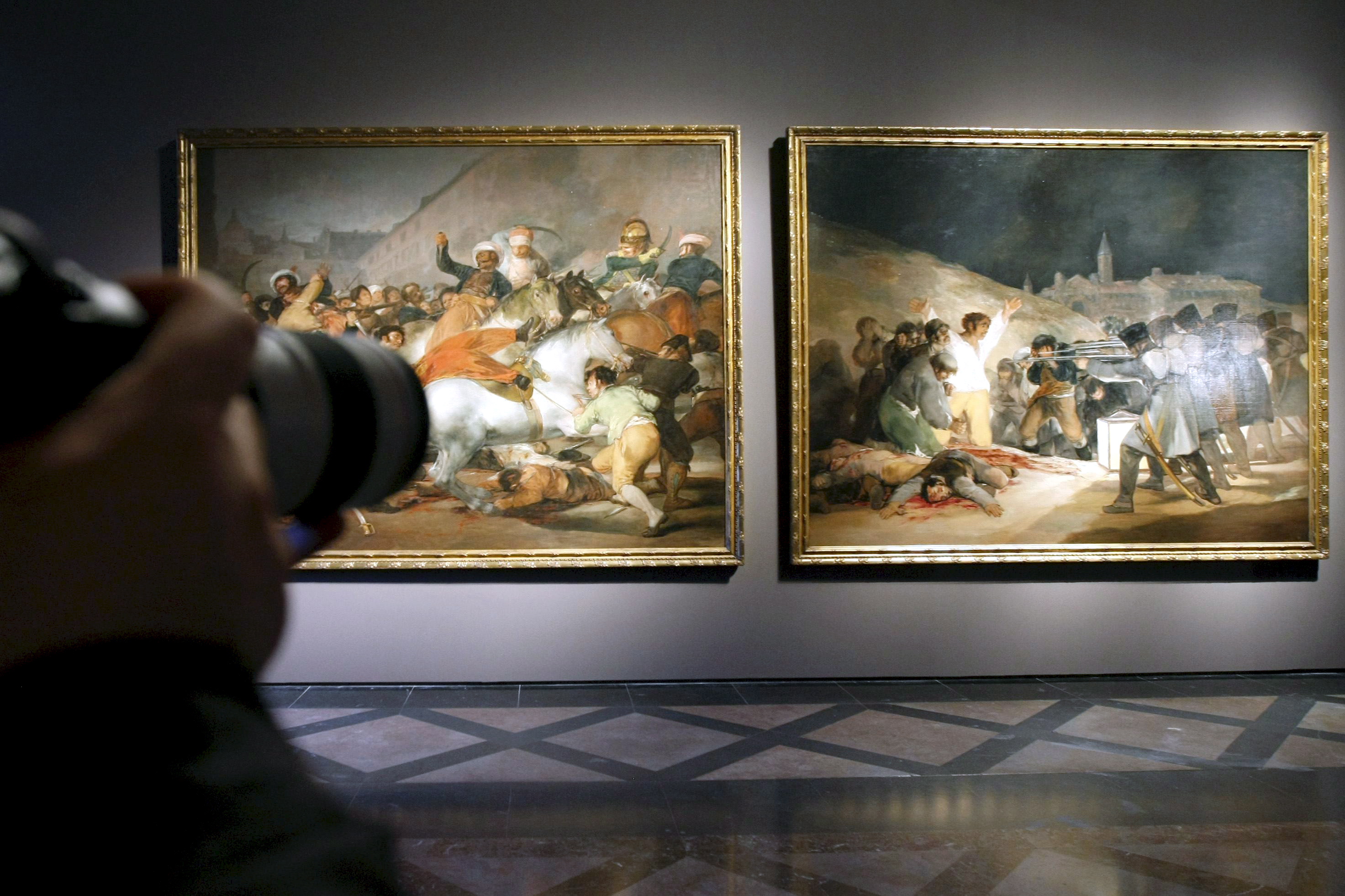 epa01308951 A man takes photos of (R-L) Goya's paintings 'Los Fusilamientos del tres de mayo' (The Third of May 1808: The Execution of the Defenders of Madrid) and 'El dos de mayo de 1808' (The second of May 1808), alsow known as 'La carga de los mamelucos' (The Charge of the Mamelukes), after their restoration, at the Prado Museum in Madrid, Spain, 09 April 2008. The paintings were placed in the new hall named 'Goya in times of war', which will be inaugurated 14 April 2008. EPA/FERNANDO ALVARADO