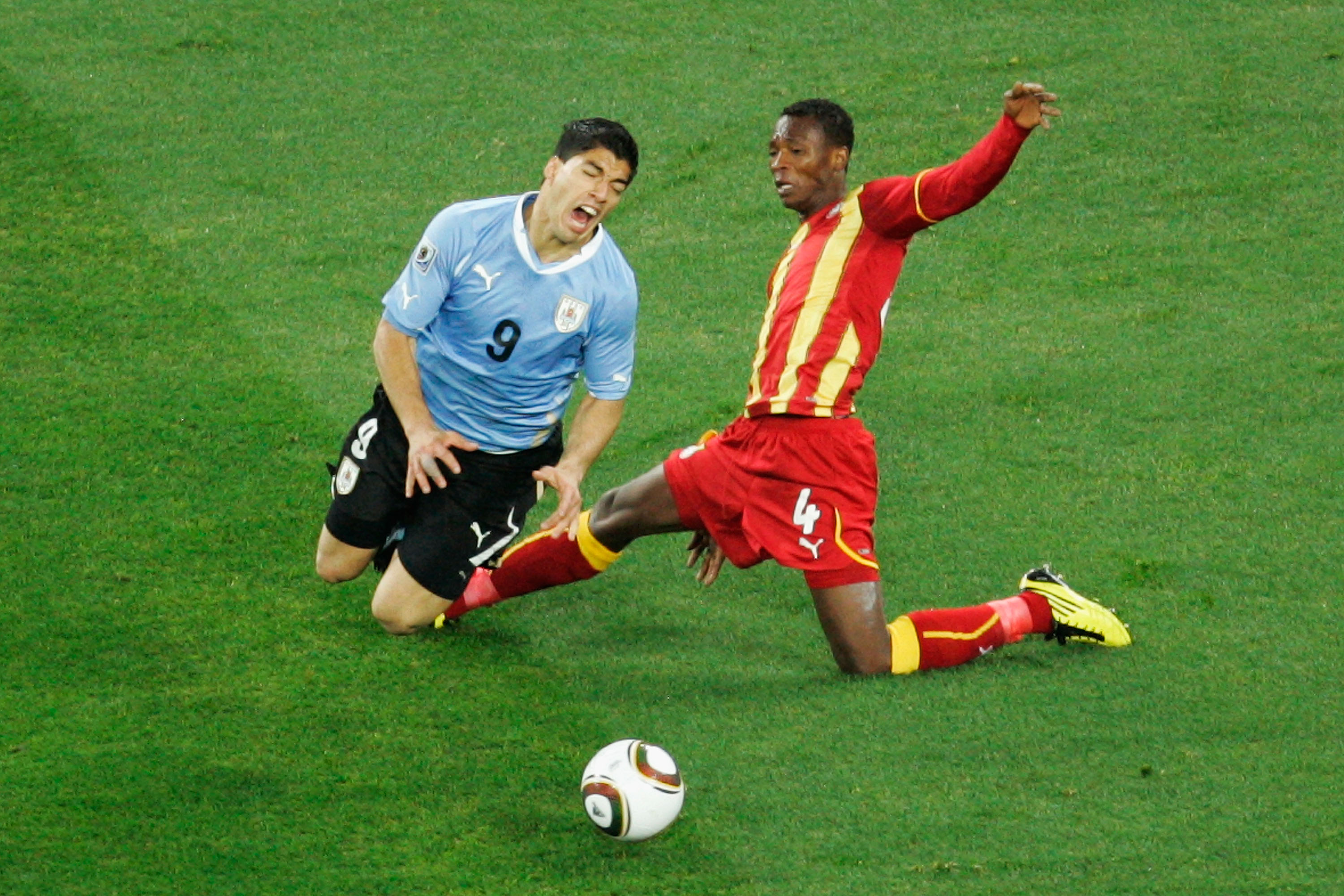John Pantsil of Ghana tackles Luis Suarez of Uruguay