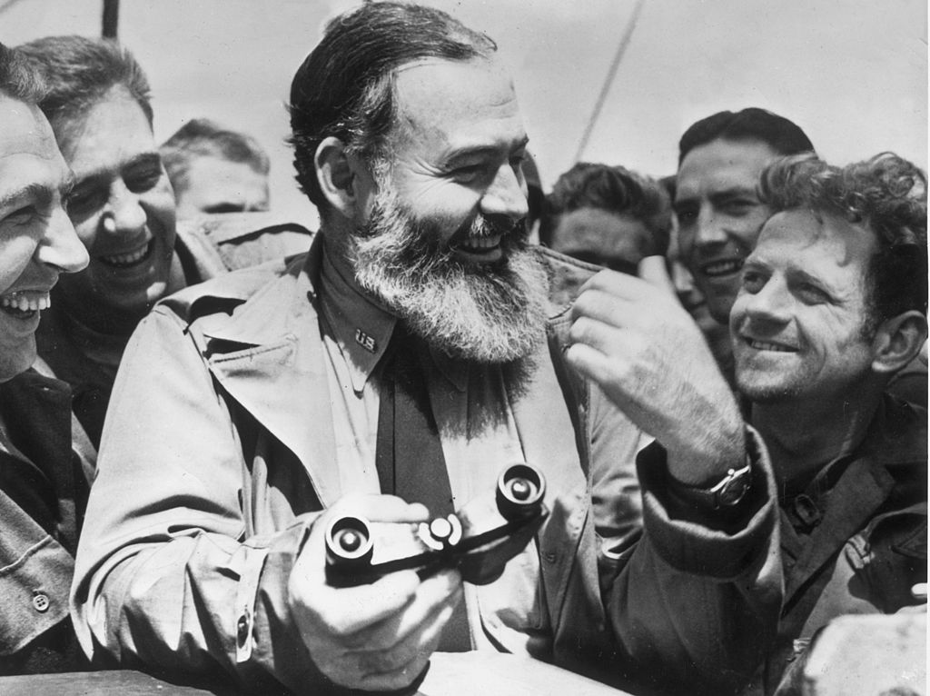 1944: American writer Ernest Hemingway (1899 - 1961) travelling with US soldiers, in his capacity as war correspondent, on their way to Normandy for the D-Day landings. (Photo by Central Press/Getty Images)