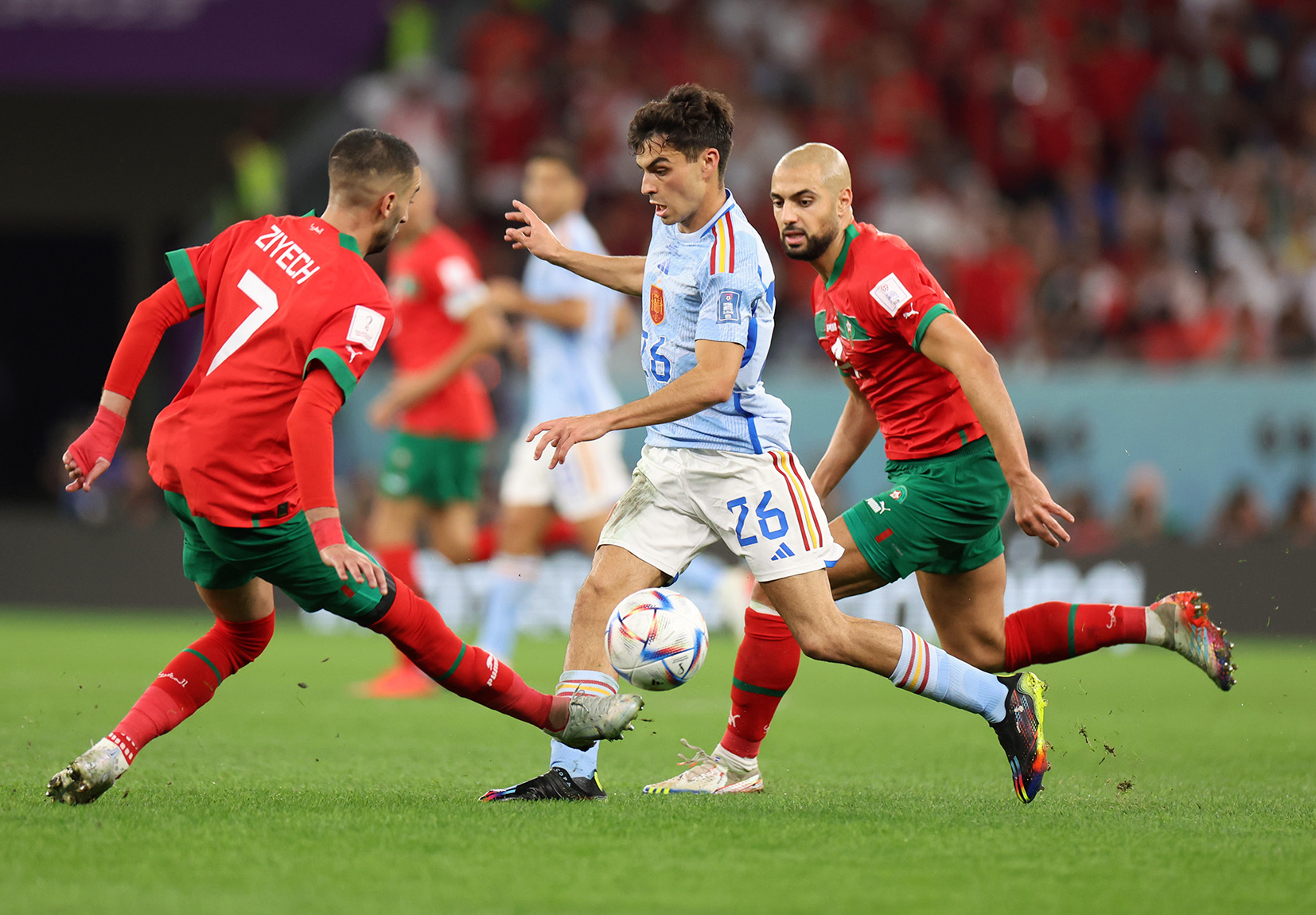 Pedri of Spain is tackled by Hakim Ziyech and Sofyan Amrabat of Morocco 