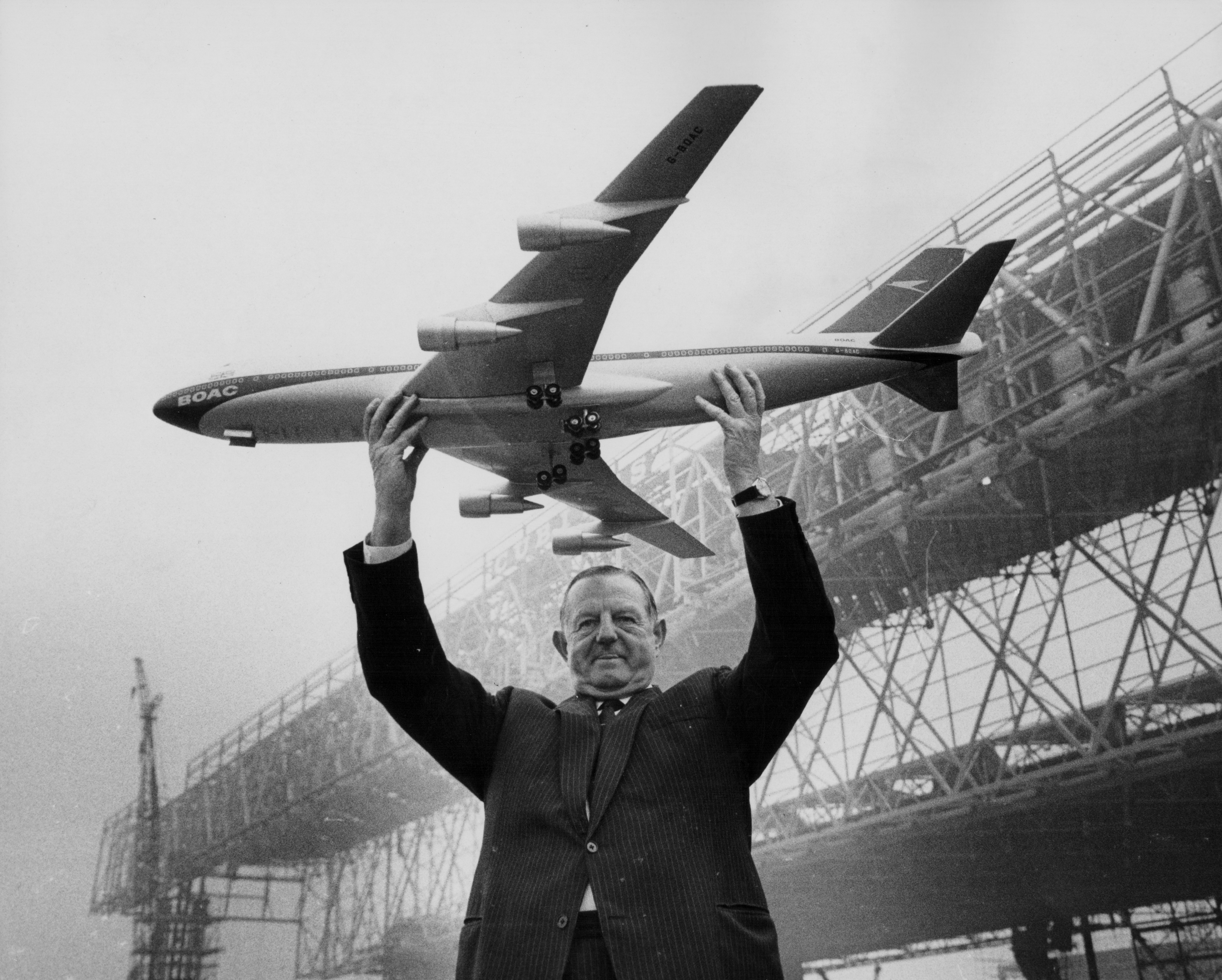 Keith Granville, Managing Director of BOAC, holding up a model of the Boeing 747 jet, with the new aircraft hangars under construction in the background, Heathrow Airport, London, March 17th 1969. Image: Jim Gray / Keystone / Getty Images