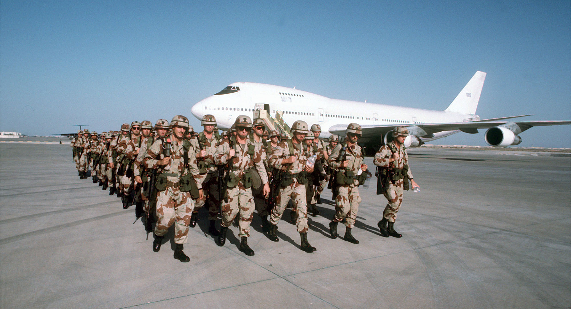 Troops march in formation after disembarking from a Civil Reserve Air Fleet Boeing 747 aircraft upon their arrival in support of Operation Desert Shield. Image: Getty / DOD