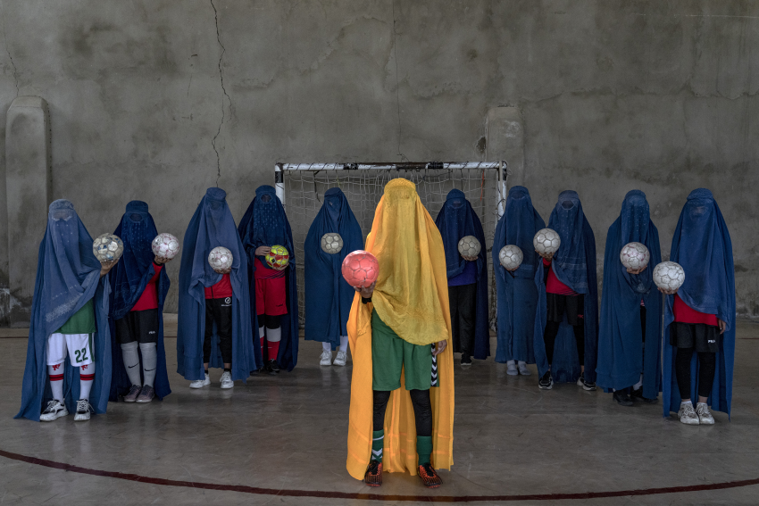 "Afghanistan’s Girl Athletes". A girls soccer team poses for a photograph while wearing a burqa. Kabul, Afghanistan, 22 September 2022. A number of women and girls who used to play sports pose for portraits with the equipment of the sports they loved. They hid their identities with their burqas, the robes and hood that cover the face, leaving only a mesh to see through. They don’t normally wear the burqa, but said they sometimes choose to when they go outside and want to remain anonymous and avoid harassment. The ban on sports is just one way the Taliban has shut down life for girls and women since their takeover in August 2021. It has also barred girls from attending middle and high school; ordered all women to be thrown out of universities; severely limited women’s ability to work outside the home; and, in November 2022, the Taliban’s Ministry of Virtue prohibited women and girls from going to parks or gyms. © Ebrahim Noroozi, Iran, Islamic Republic Of, Finalist, Professional competition, Portraiture, Sony World Photography Awards 2023