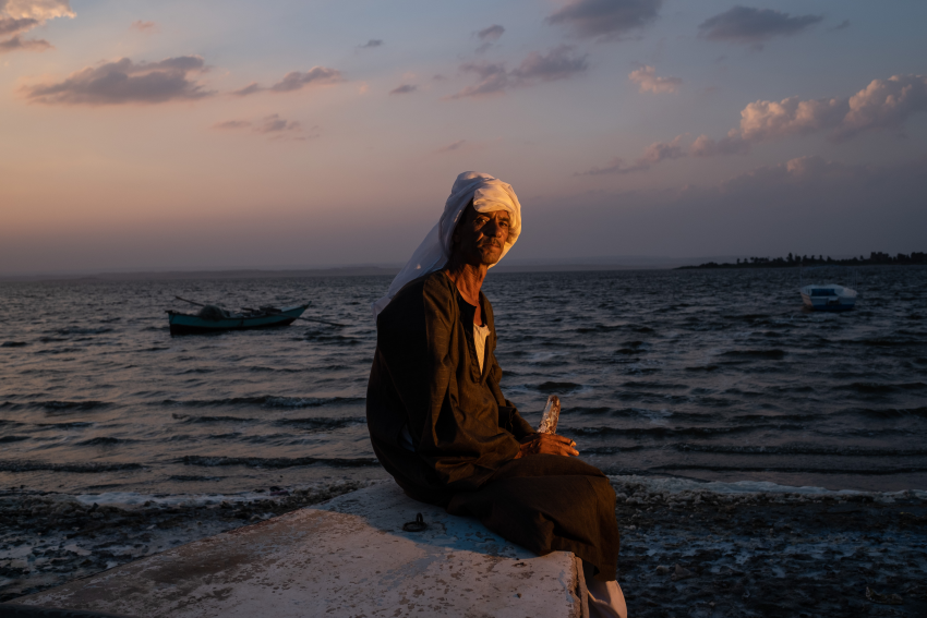 "The Lost Lake 4". Darabala Abdel Hadi (61) poses for a portrait on the shore at Lake Qarun. Darabala worked with his father for 20 years as a fisherman on the lake, but when fish stocks declined sharply due to severe pollution, he was forced to abandon Ezbat Soliman and move to the village of Abu Simbel in the south of Egypt. Lake Qarun, located in the Fayoum in south west Egypt, is one of the oldest lakes in the world, containing fossils that are millions of years old. During the Pharaonic era, flooding meant that this low-lying lake was supplied with freshwater from the Nile, but since the start of the 20th Century it has grown increasingly saline. Various fish species have already disappeared due to increased pollution and changes to the climate, and the health of Lake Qarun and the wildlife within it are now seriously endangered by its rising saline level, which is higher than that of seawater. To compound this, a parasitic infection has spread throughout the lake, which has negatively impacted fish production and quality, thereby harming the fishing community in Fayoum: the number of fishing boats operating in the lake has decreased from 605 to just 10 boats. This project attempts to explore the lives of the fishermen residing in the village of Ezbat Soliman, near Lake Qarun, and how the lake’s pollution affects them. © Fatma Fahmy, Egypt, Shortlist, Professional competition, Environment, Sony World Photography Awards 2023