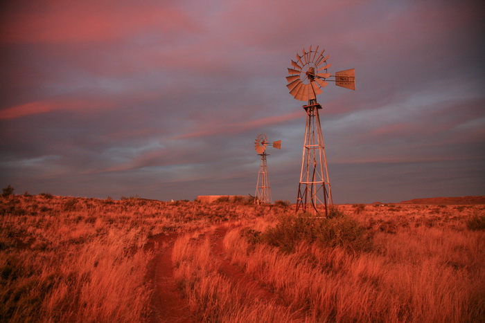 A couple of wind pumps outside Carnarvon in the red hue of sunset. Image: Chris Marais