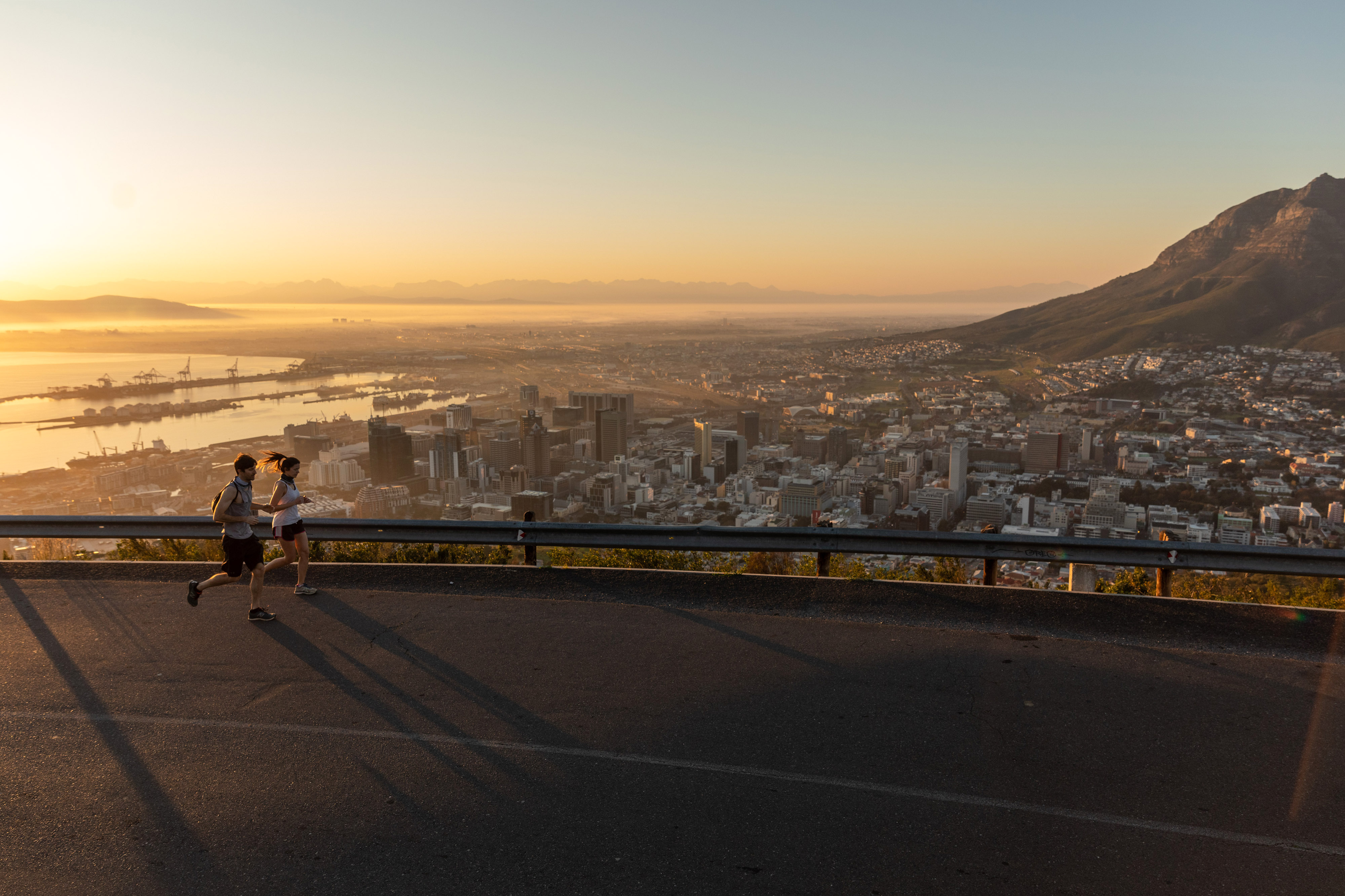 Joggers make their way up a hill as the port area and commercial high-rise properties stand at the foot of Table mountain as the sun rises in Cape Town, South Africa, on Thursday, July 23, 2020. South Africas surging coronavirus infections and the resumption of rolling blackouts are clouding the outlook for the economy. Photographer: Dwayne Senior/Bloomberg via Getty Images