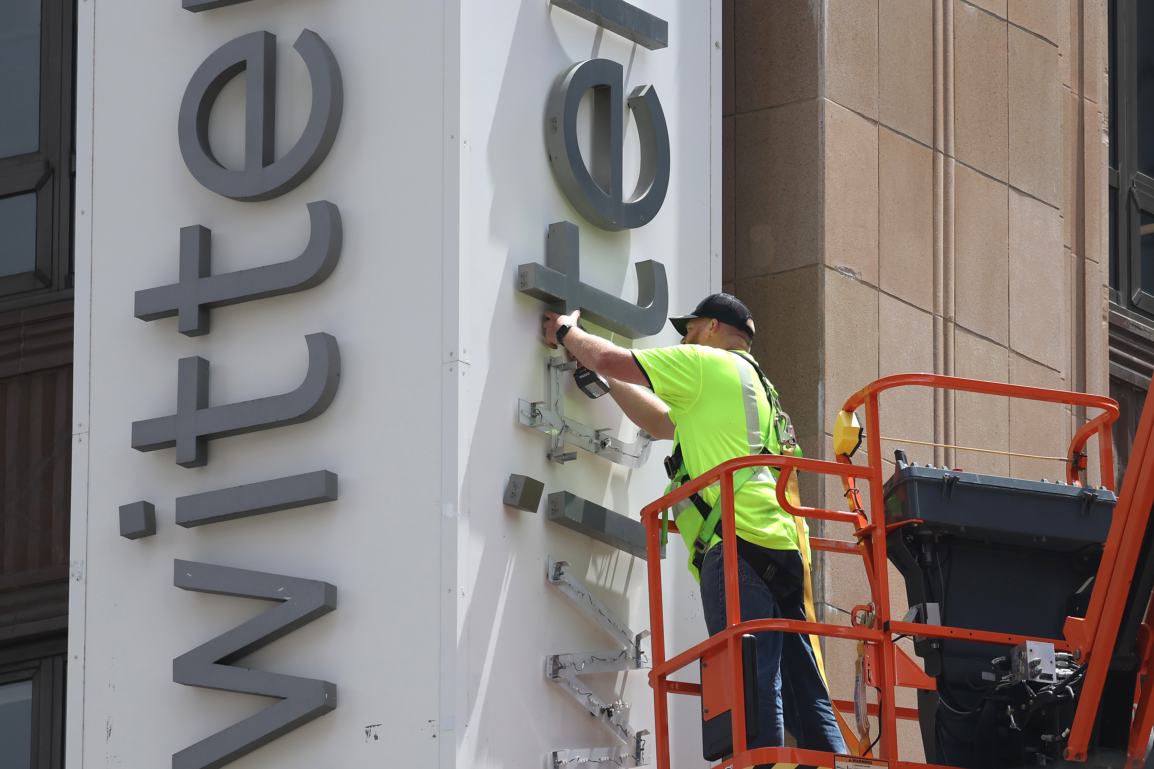 A worker removes letters from the Twitter sign that is posted on the exterior of Twitter headquarters on July 24, 2023 in San Francisco, California. Workers began removing the letters from the sign outside Twitter headquarters less than 24 hours after CEO Elon Musk officially rebranded Twitter as "X" and has changed its iconic bird logo, the biggest change he has made since taking over the social media platform. San Francisco police halted the sign removal shortly after it began. (Photo by Justin Sullivan/Getty Images)