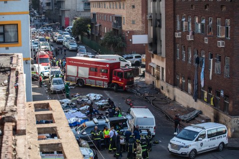 Fire crews and emergency staff stand next to the covered bodies of the victims as they gather at the site of a fire that broke out at the five-storey building in the city centre, in Johannesburg, South Africa, 31 August 2023. (Photo: EPA-EFE / Kim Ludbrook)