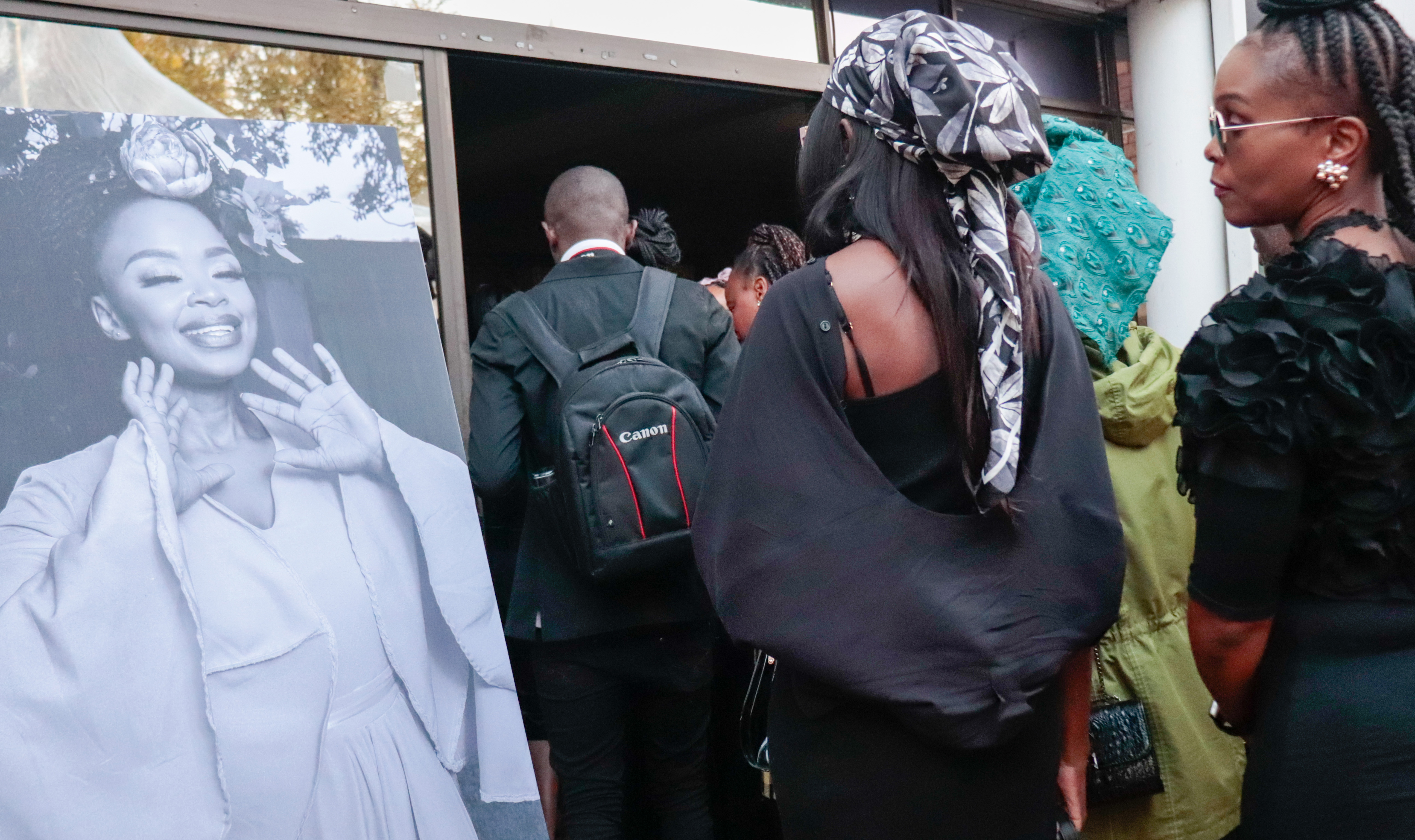 Mourners walk past a portrait of Zoleka Mandela