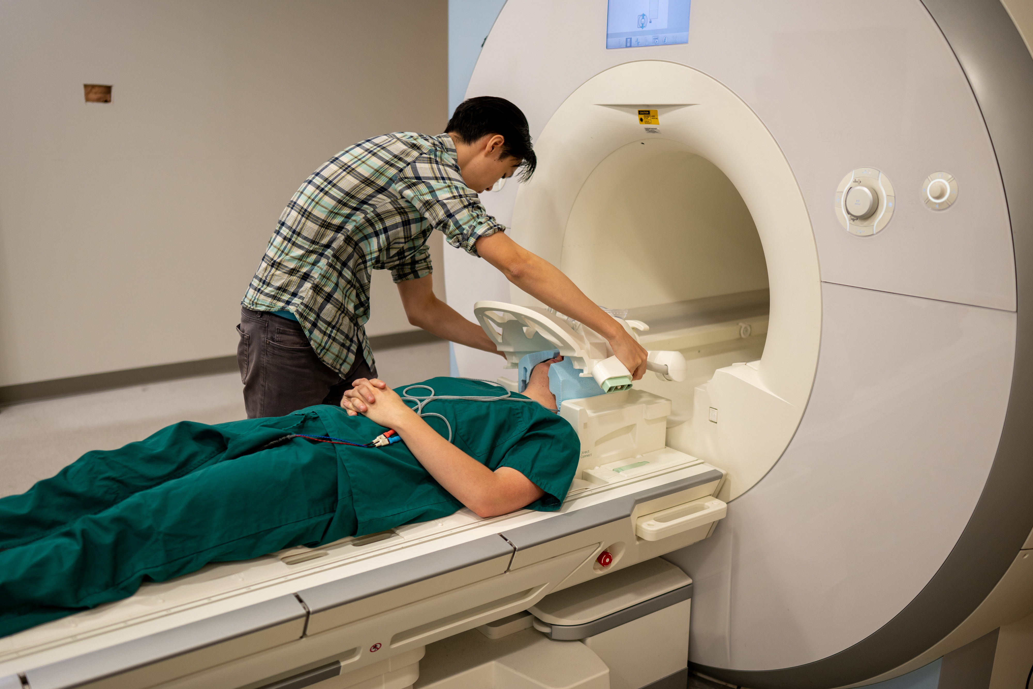 Ph.D. student Jerry Tang prepares to collect brain activity data in the Biomedical Imaging Center at the University of Texas at Austin. The researchers trained their semantic decoder on dozens of hours of brain activity data from participants, collected in an FMRI scanner. Image: Nolan Zunk/University of Texas at Austin.